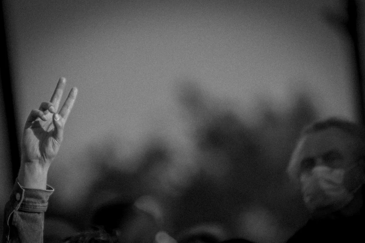 Raised hand making a peace sign in a blurred crowd